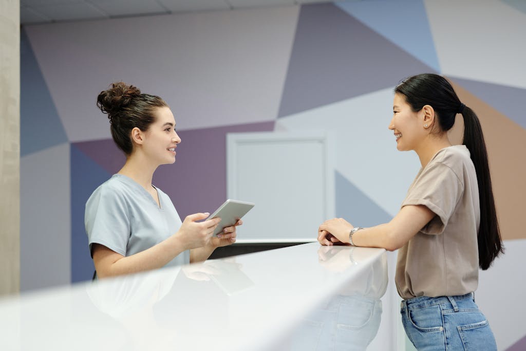 A receptionist and a visitor engaging at a modern reception desk, indoors.